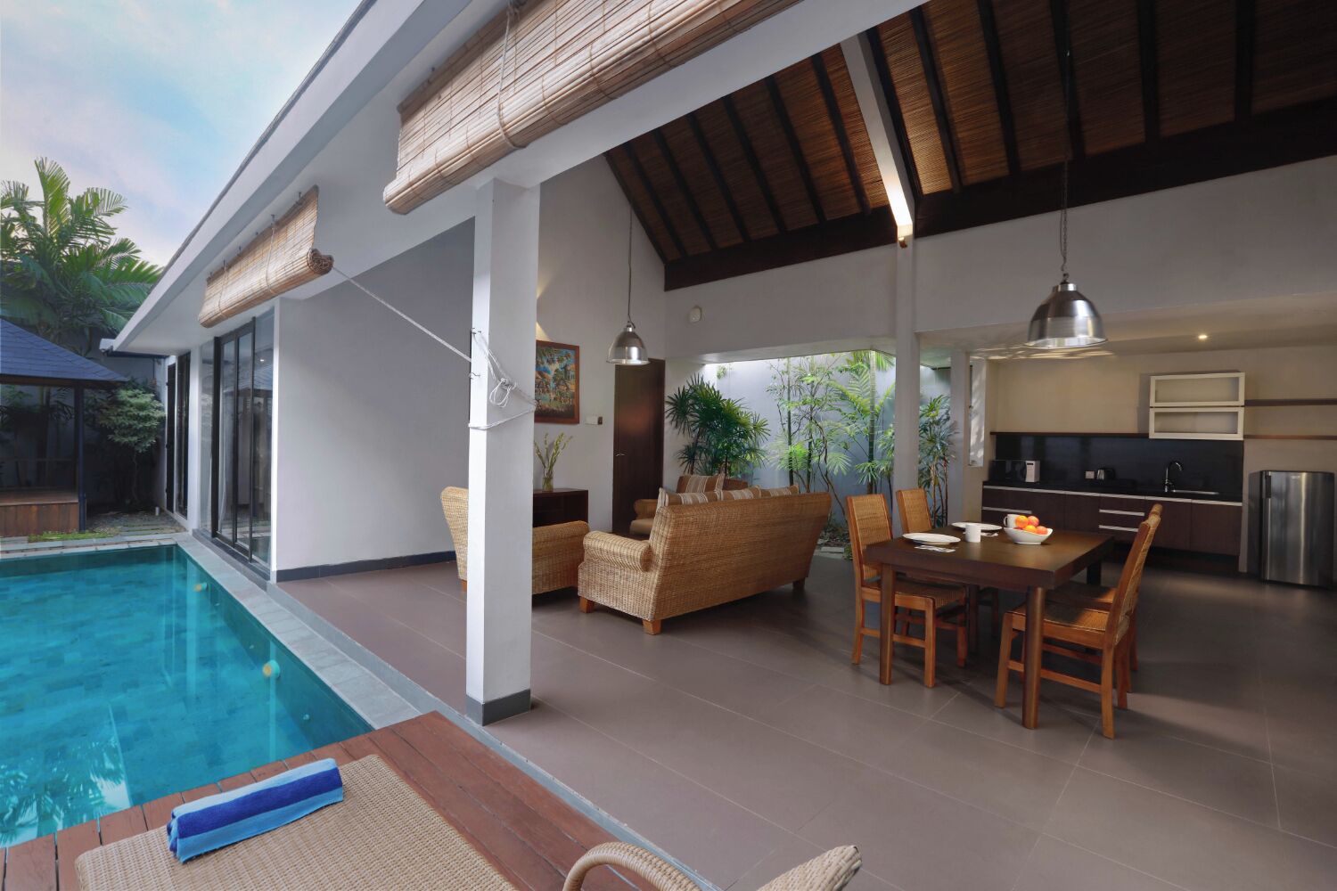 Un'area piscina interna moderna con zona pranzo, cucina e salotto.