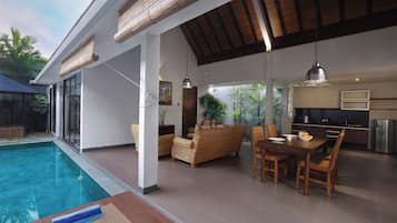 Un'area piscina interna moderna con zona pranzo, cucina e salotto.