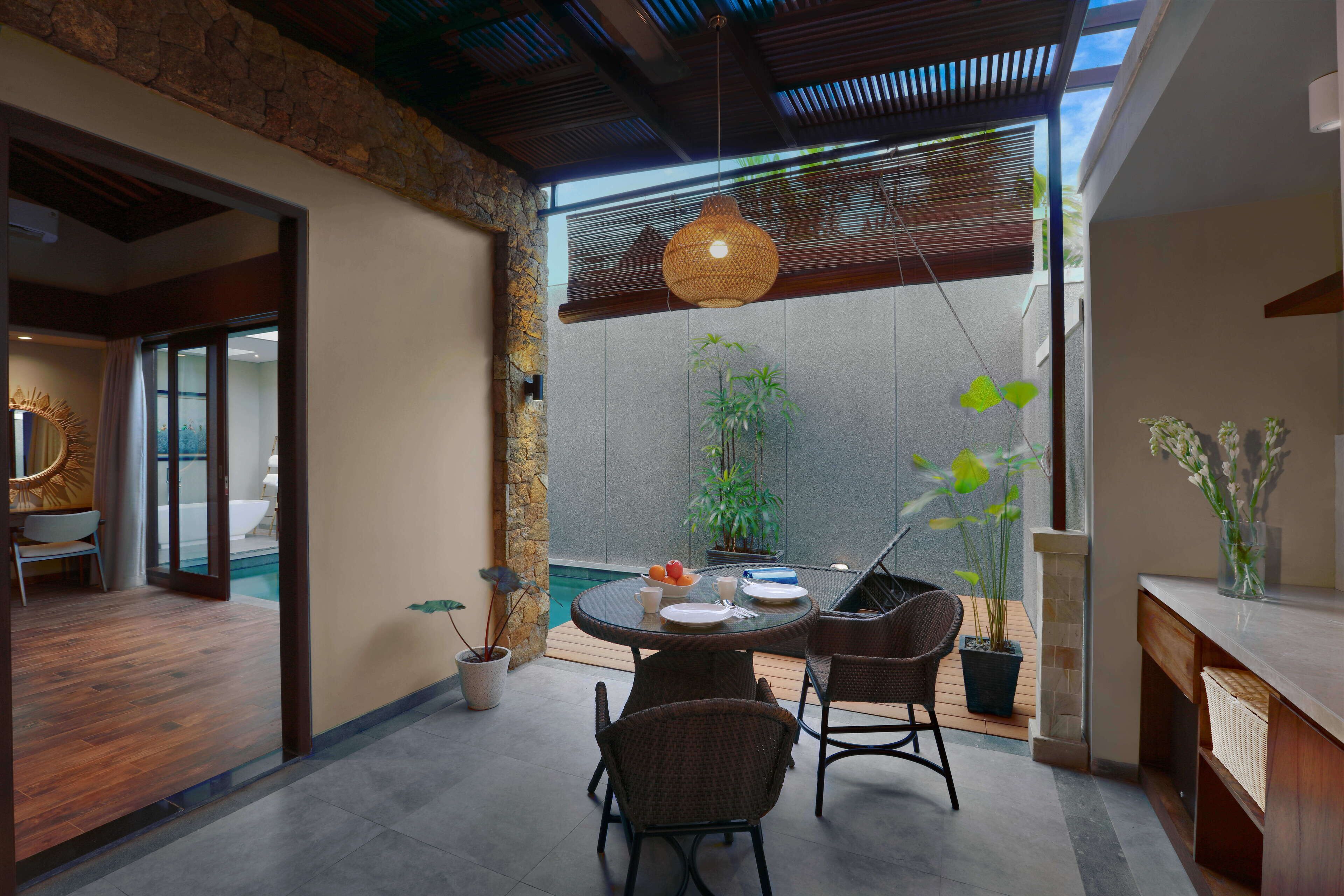 A modern dining area with a round table, chairs, and a hanging light fixture.