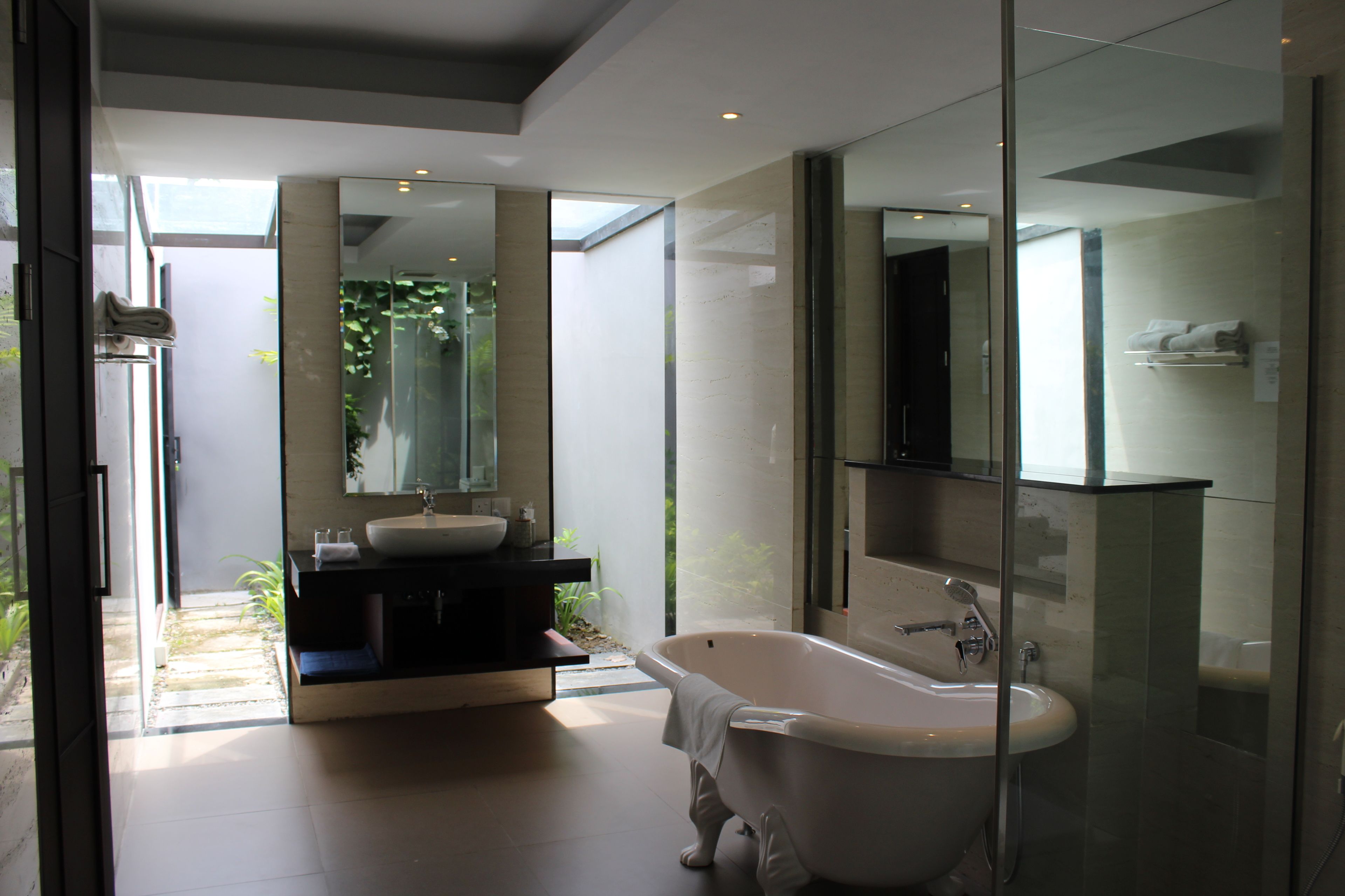 Un baño moderno con una bañera independiente, un espejo grande y una zona de ducha con mampara de cristal.