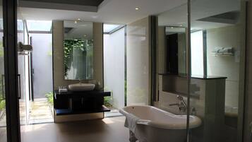 Un baño moderno con una bañera independiente, un espejo grande y una zona de ducha con mampara de cristal.