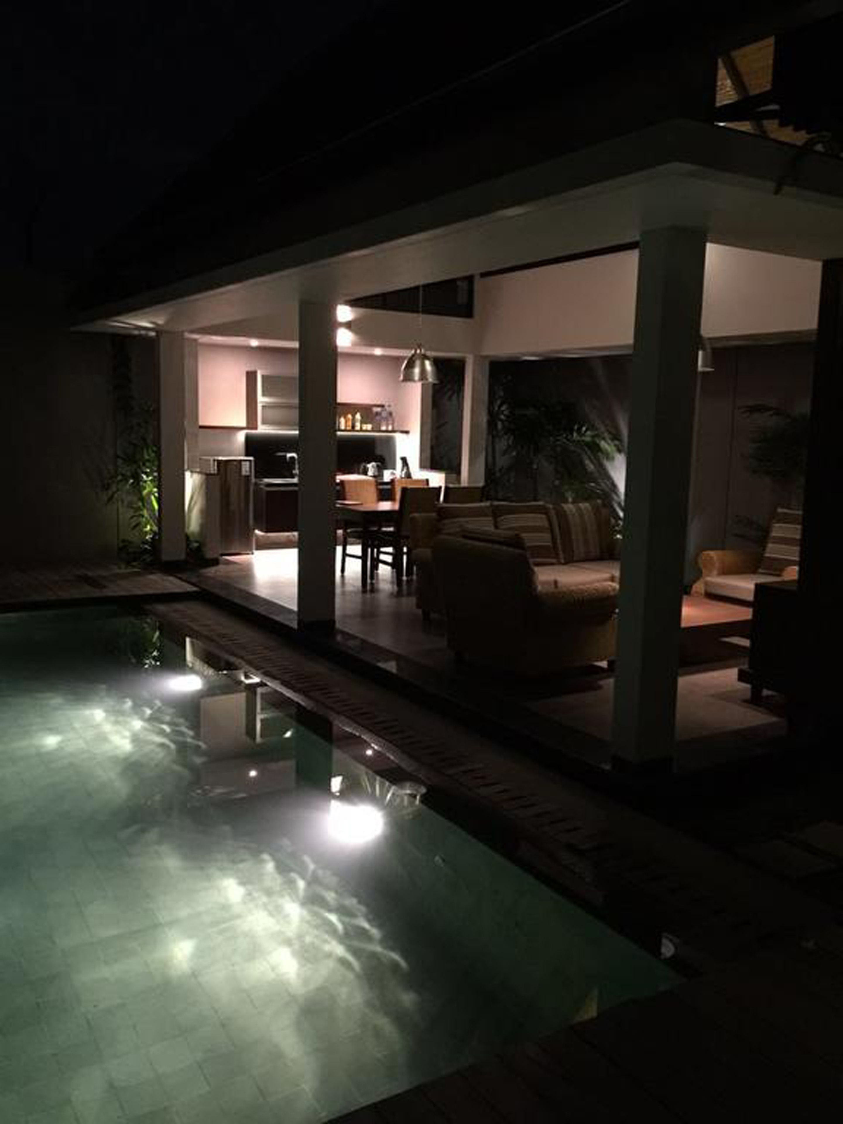A modern outdoor living area with a pool, a dining area, and a kitchen.