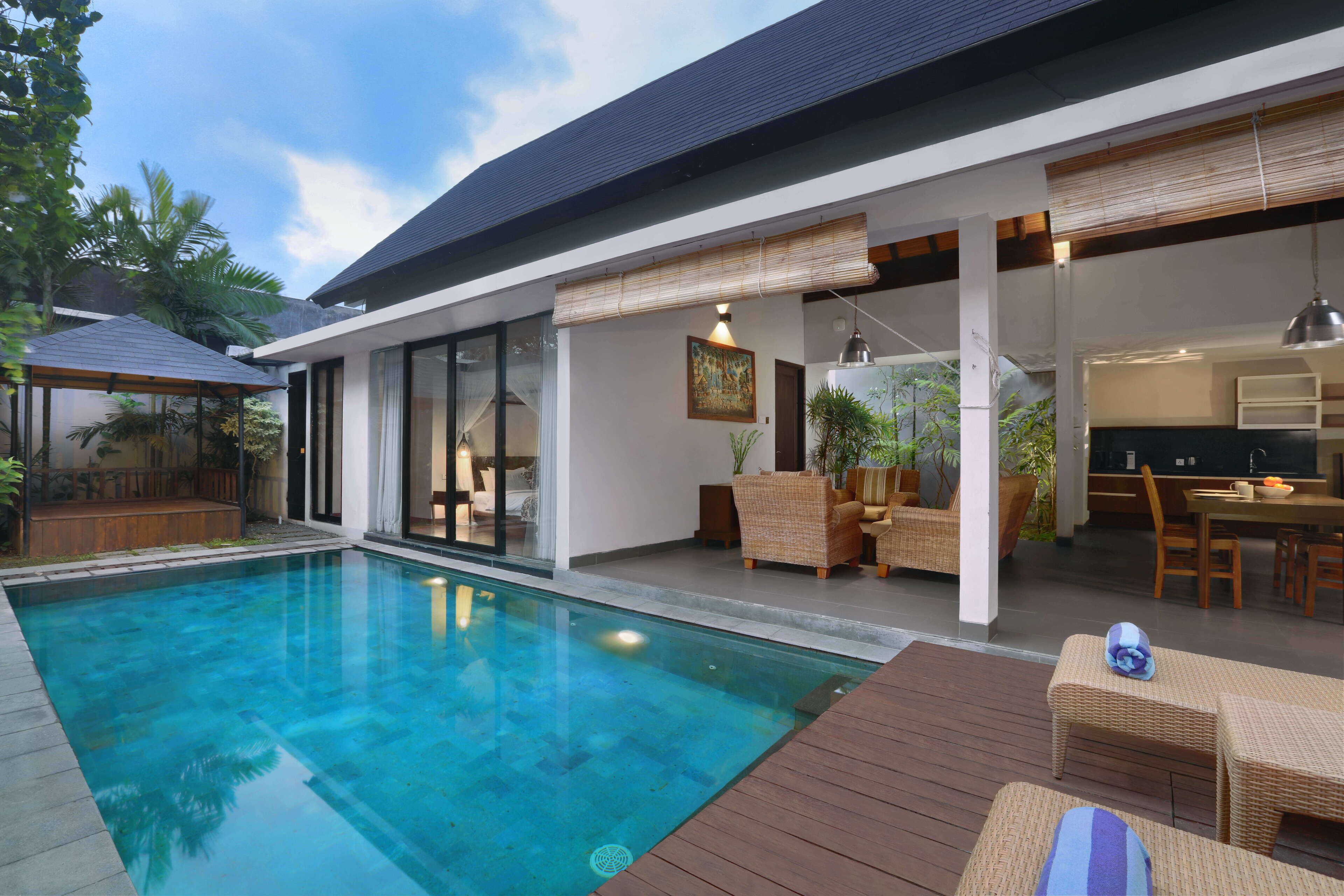 Una casa moderna con piscina, mobiliario exterior y una zona de cocina.