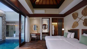 A hotel room with a large bed, a desk with a chair, a round mirror, a bathroom with a sink and mirror, and a small pool area. - Kamuela Villas Lagoi Bay Bintan (Bintan)