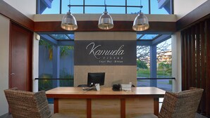 A reception desk with a sign reading "Karauela Villas Lagoon Bay - Bintan," two wicker chairs, and pendant lighting. - Kamuela Villas Lagoi Bay Bintan (Bintan)