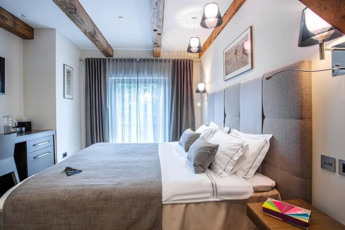A hotel room with a large bed, bedside tables, a desk, and a window with curtains.