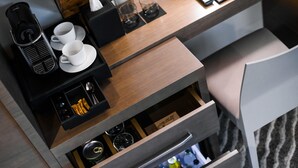 Cozinha moderna com cafeteira, duas xícaras e uma gaveta com diversos objetos.