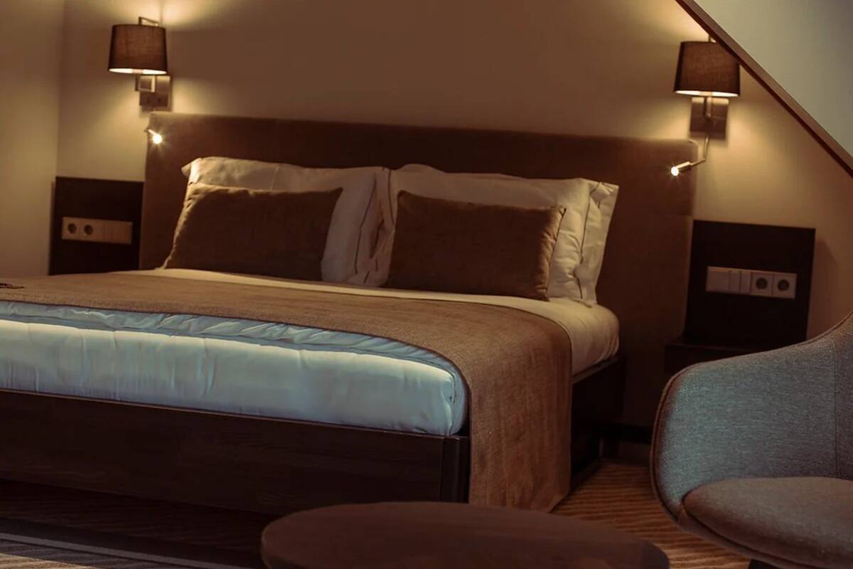 A hotel room with a large bed, two bedside tables, a chair, and a small table.