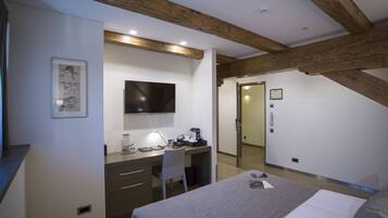 Un dormitorio con cama, escritorio, silla y televisor en la pared.