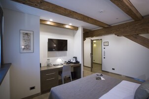 Un dormitorio con cama, escritorio, silla y televisor en la pared.