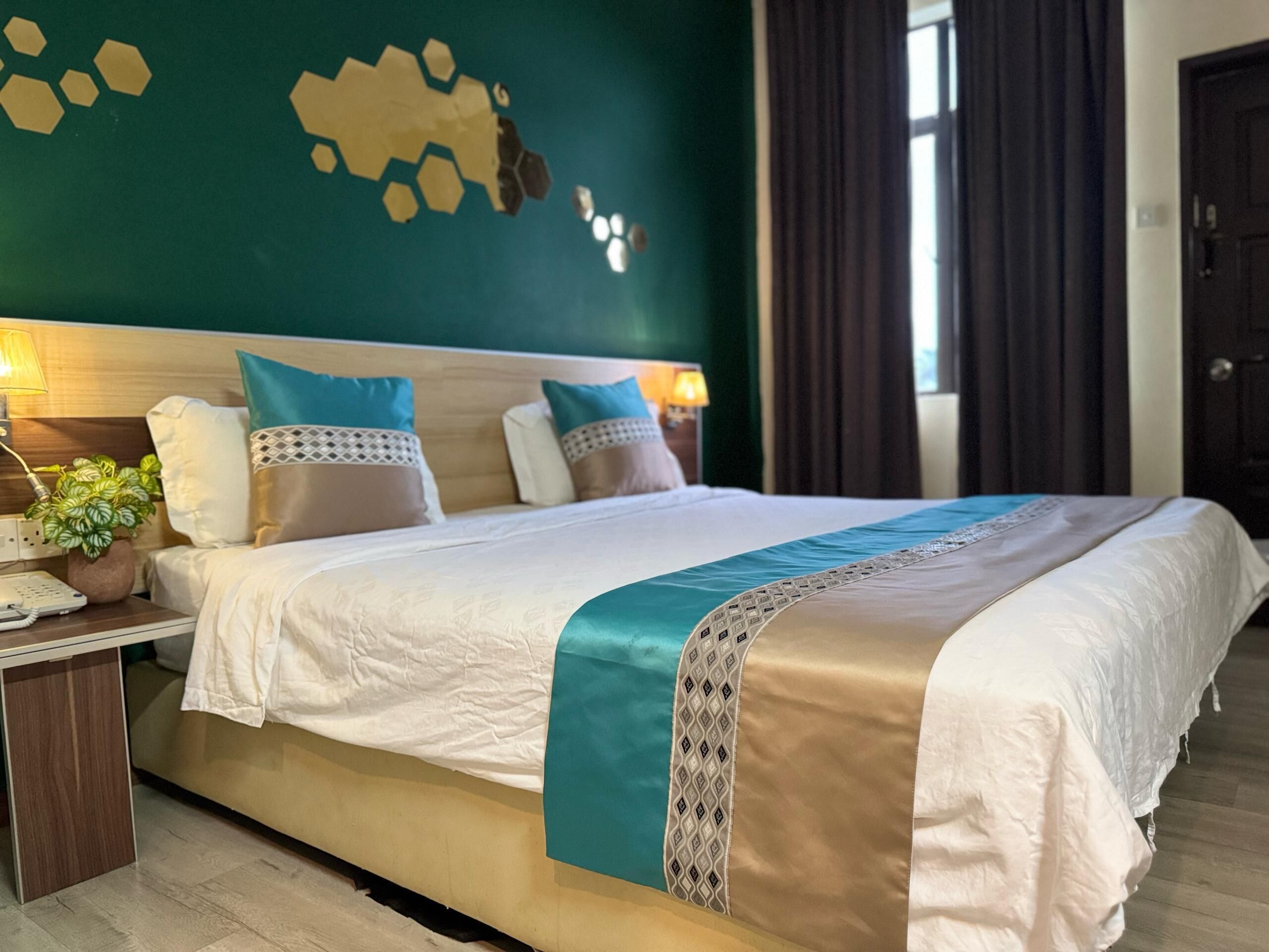 A neatly made bed with a patterned bedspread, a bedside table with a lamp, and a wall decoration.