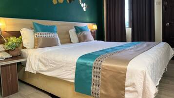 A neatly made bed with a patterned bedspread, a bedside table with a lamp, and a wall decoration.