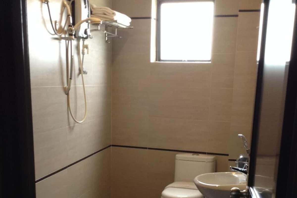 A small bathroom with a toilet, sink, and shower.