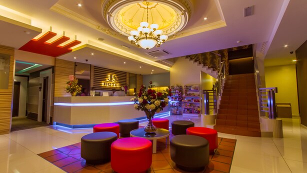 A hotel lobby with a reception desk, a chandelier, red and black seating, and a staircase. - JS Hotel (Johor Bahru)