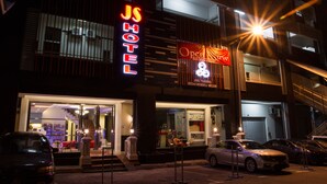 A hotel with a neon sign, a visible entrance, and parked cars. - JS Hotel (Johor Bahru)