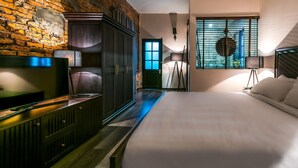 A modern hotel room with a large bed, a TV, a wardrobe, and a brick wall. - Oliving Residence (Hanoi)