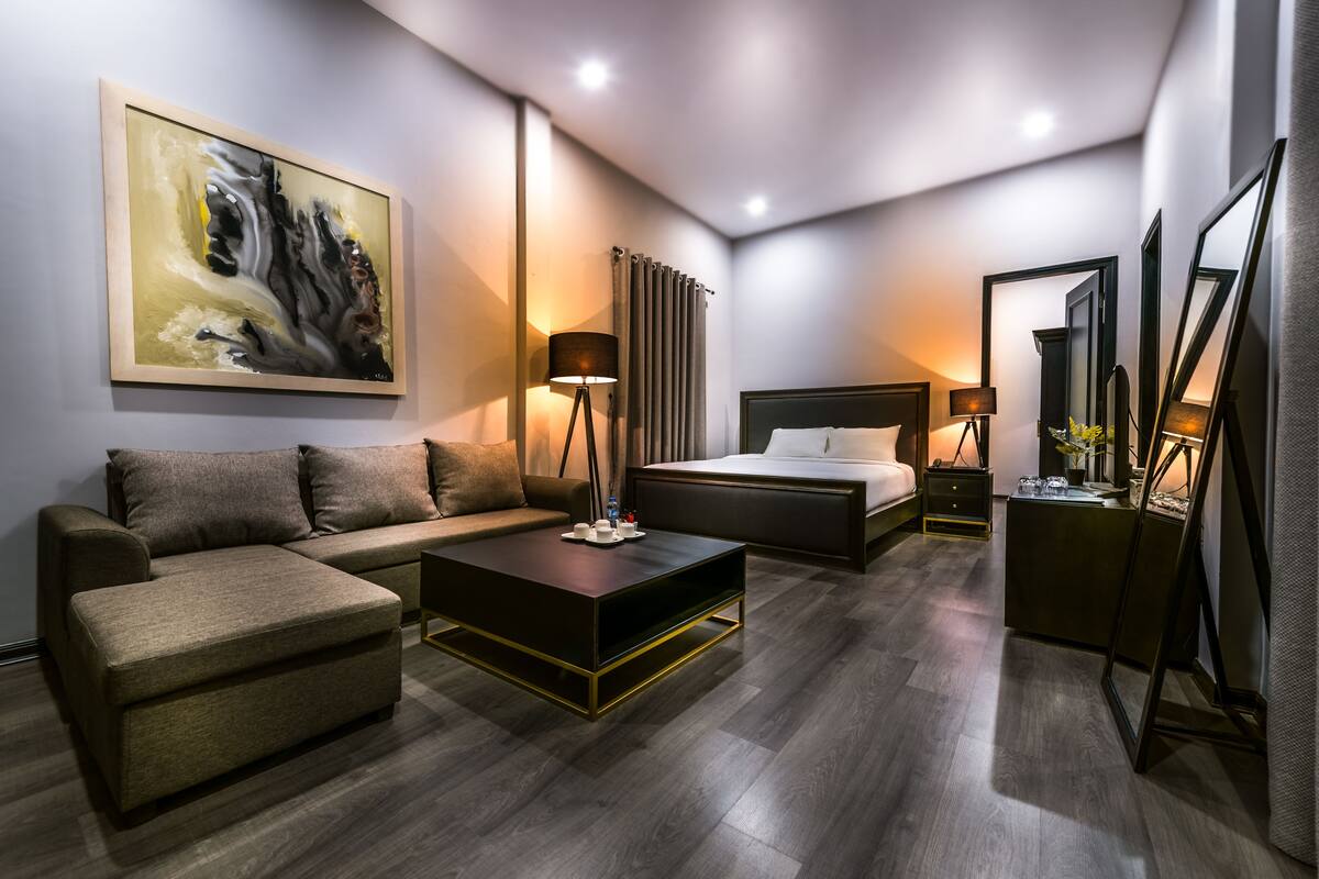 Ein modernes Hotelzimmer mit einer Couch, einem Bett, einem Couchtisch und einem Gemälde an der Wand.