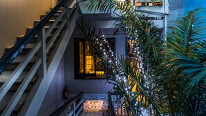 A multi-level residential building with a staircase, balconies, and indoor plants. - Oliving Residence (Hanoi)