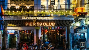 Pier 50 Club with a neon sign, outdoor seating, and parked scooters. - Oliving Residence (Hanoi)