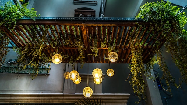 A wooden pergola with hanging lights and greenery. - Oliving Residence (Hanoi)