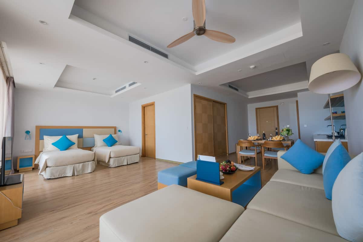 Una habitación de hotel moderna con dos camas, un sofá, un comedor y una cocina.