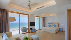 A modern hotel room with a large bed, a sofa, a coffee table, and a TV.