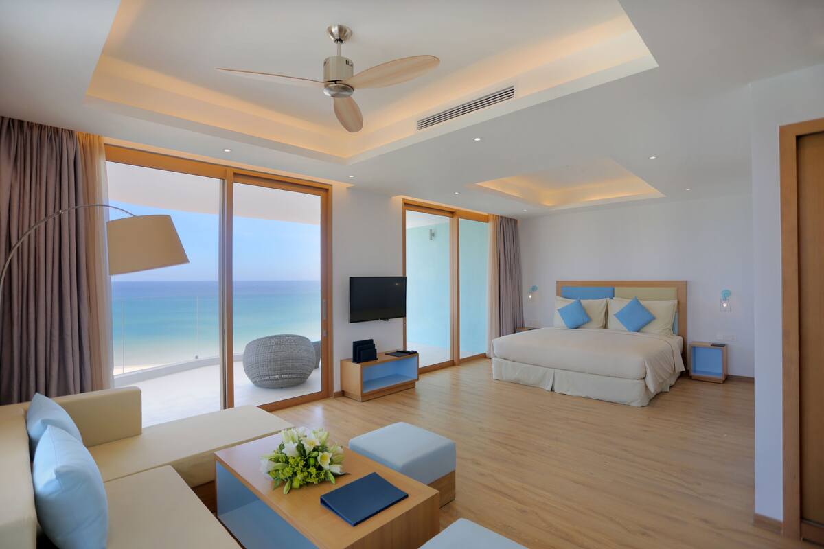 Una habitación de hotel moderna con una cama grande, un sofá, una mesa de centro y un televisor.