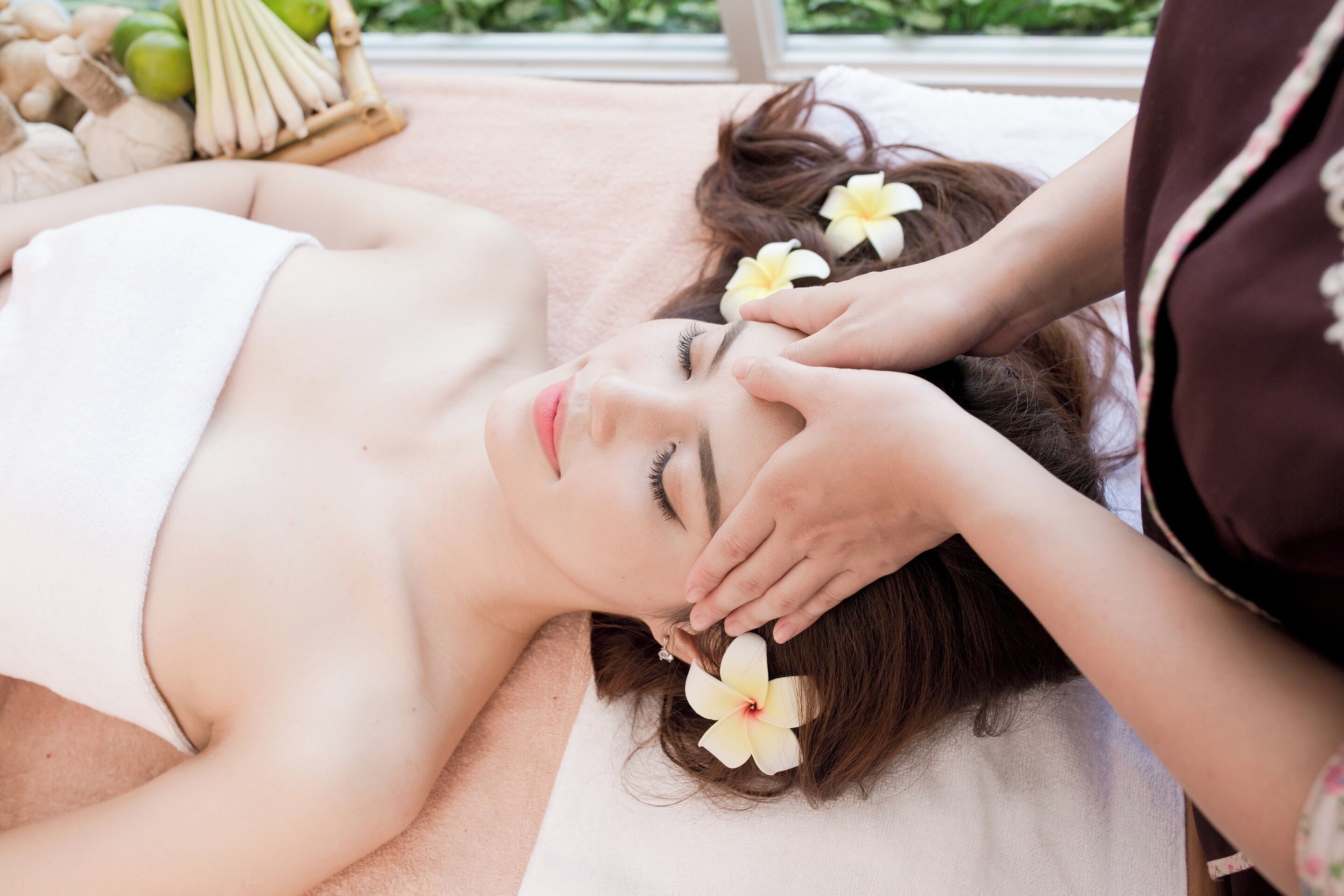 A person lying on a massage table receiving a facial treatment.