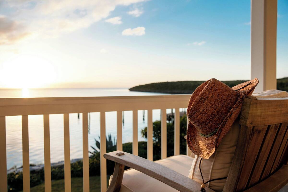 A wooden chair with a cushion on a balcony overlooking a body of water.