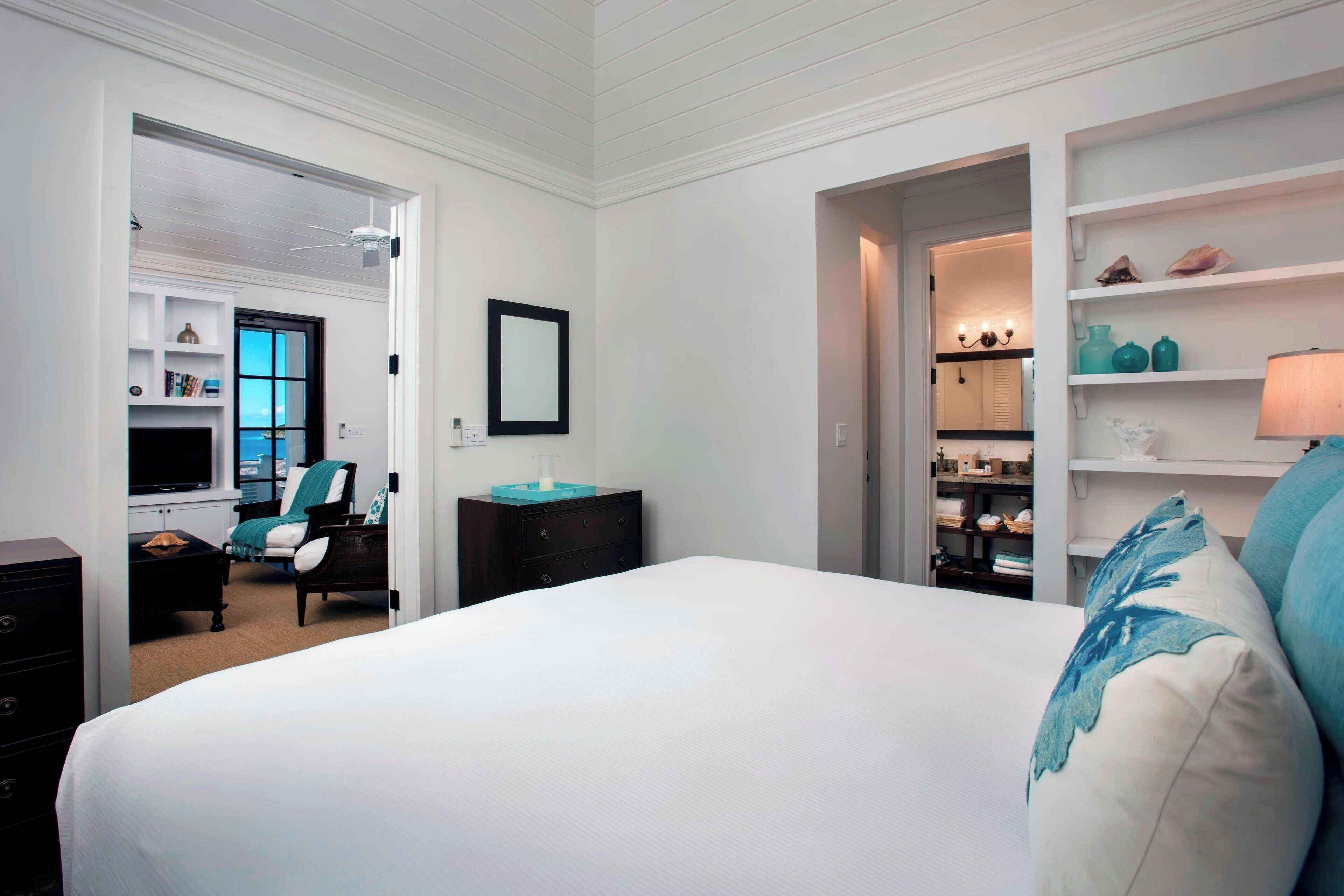 Une chambre à coucher avec un grand lit, une chaise, une commode et un téléviseur dans un coin.