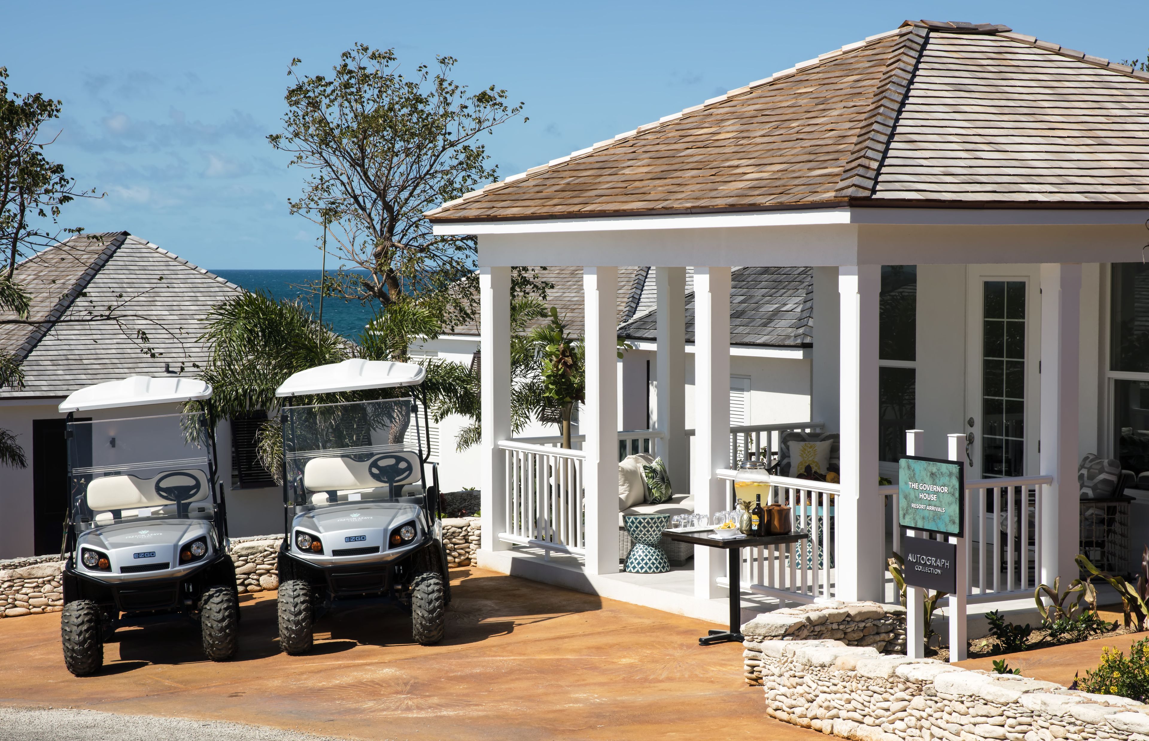 A white building with a covered porch, two golf carts, and a sign indicating an autograph collection.