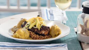 Une assiette de nourriture, un verre de vin blanc, une serviette rayée et un bocal en verre contenant une étoile de mer.