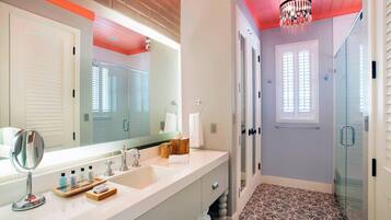 A modern bathroom with a large mirror, a sink, and a shower area.
