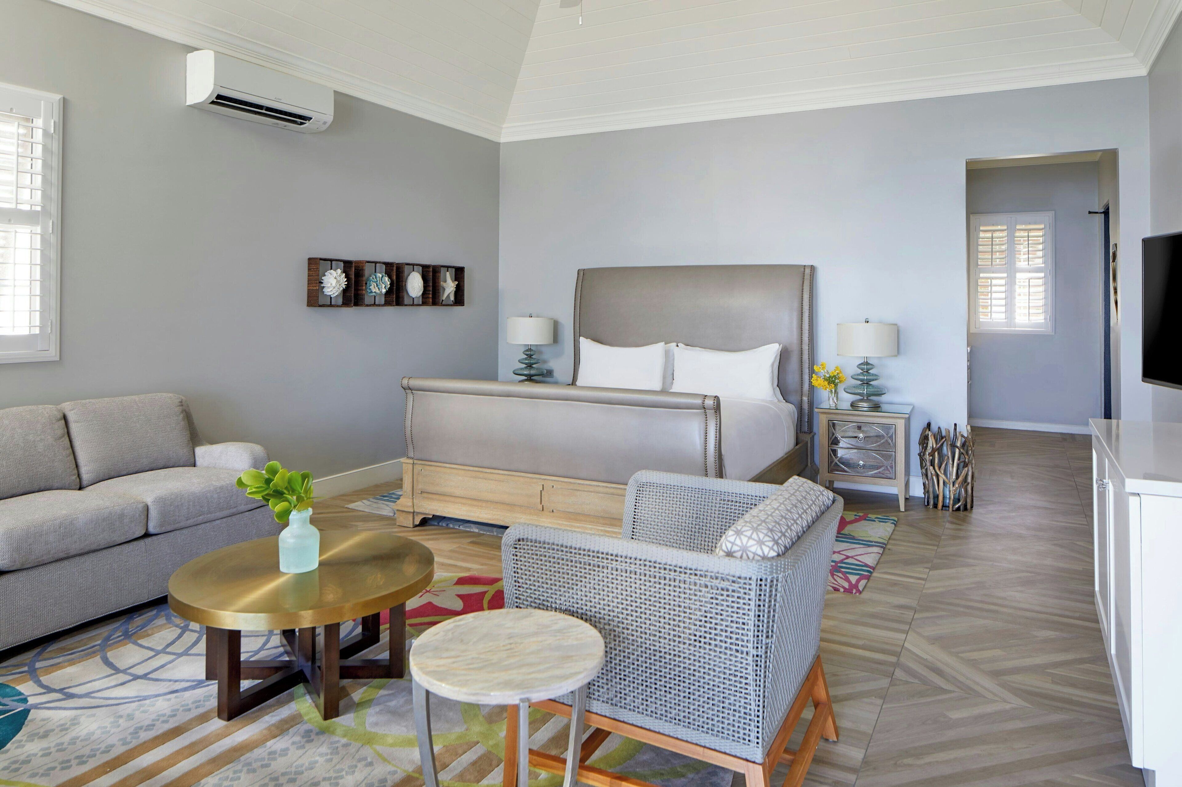 Un dormitorio con una cama, un sofá, una silla, una mesita y un televisor.
