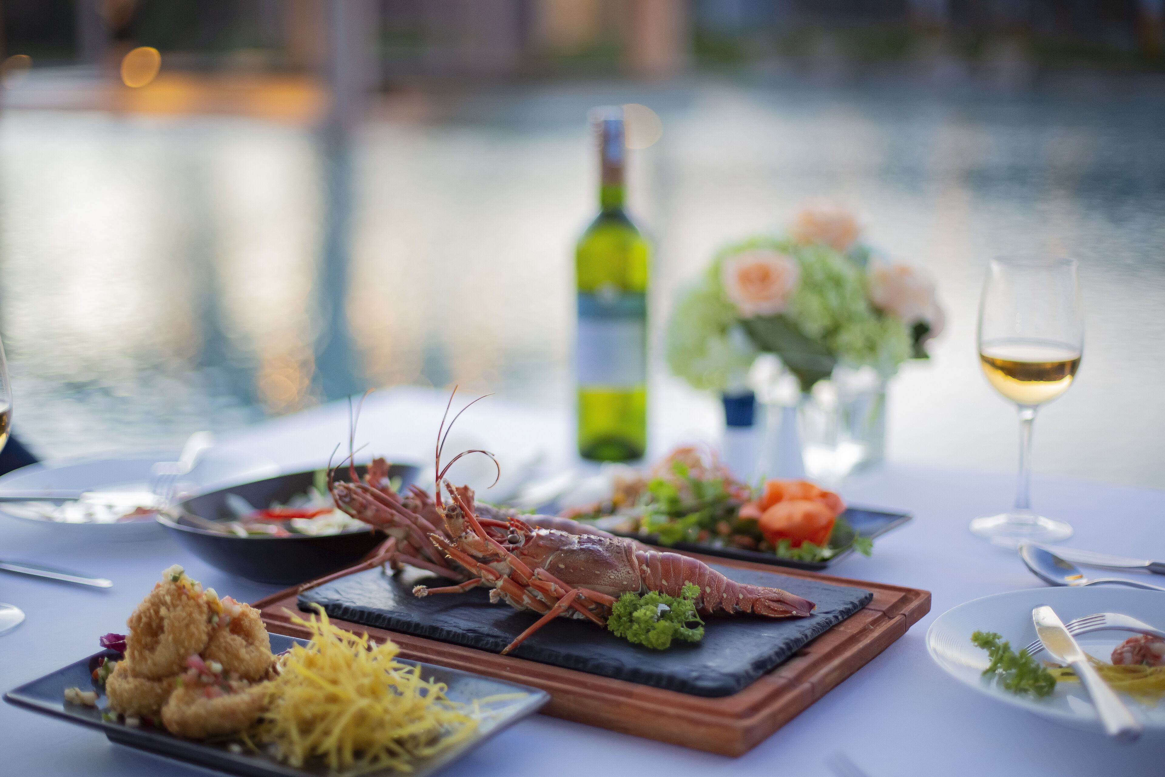 A dining table with seafood dishes, a wine bottle, and a glass of wine.