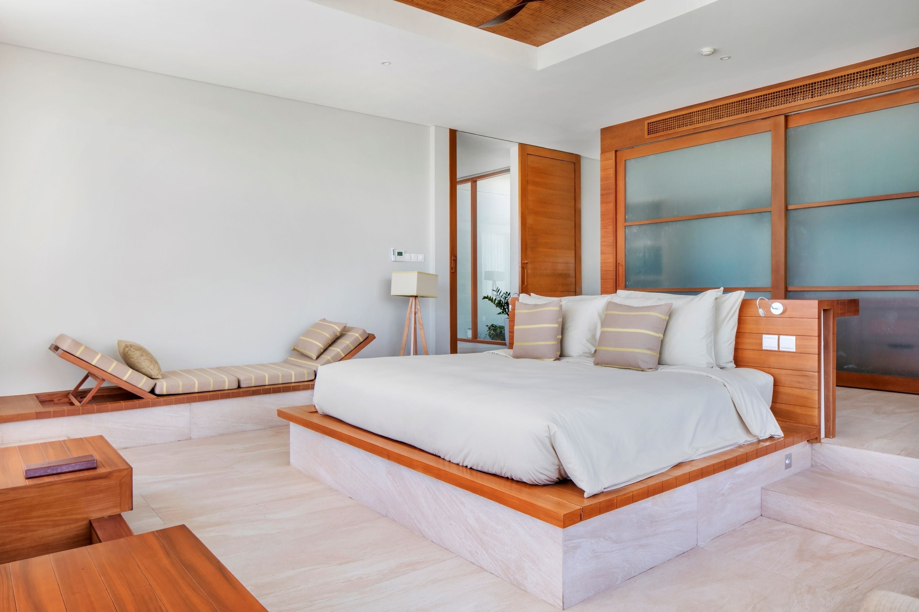 A modern bedroom with a large bed, built-in seating, and a wooden headboard.