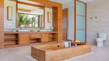 A modern bathroom with a wooden vanity, a large mirror, a freestanding bathtub, and a toilet.