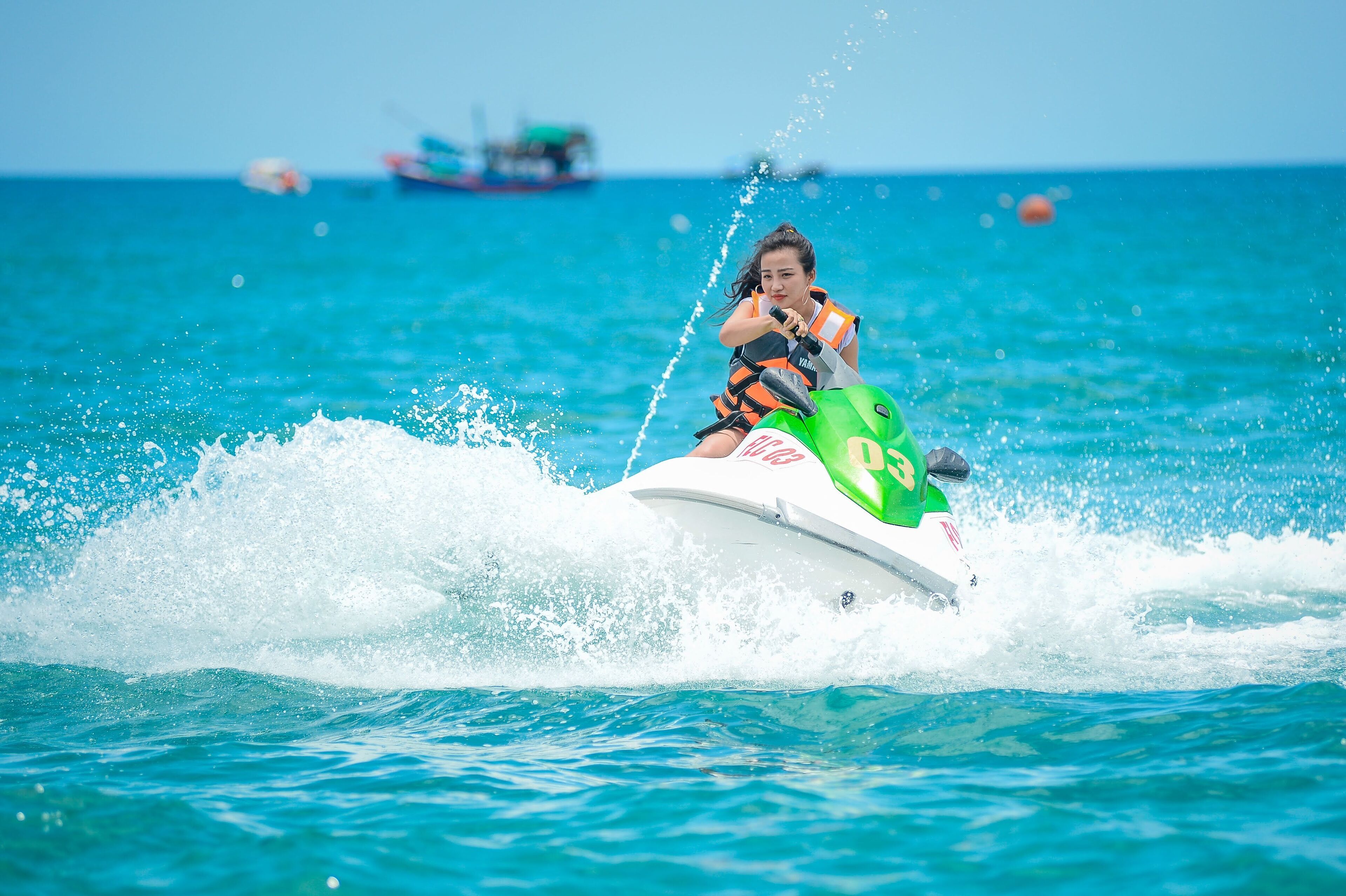 A person jet-skiing on a clear day with calm waters and distant boats.