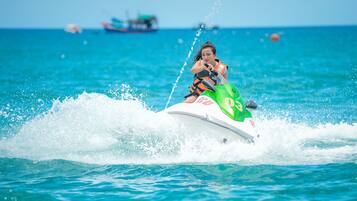 A person jet-skiing on a clear day with calm waters and distant boats.
