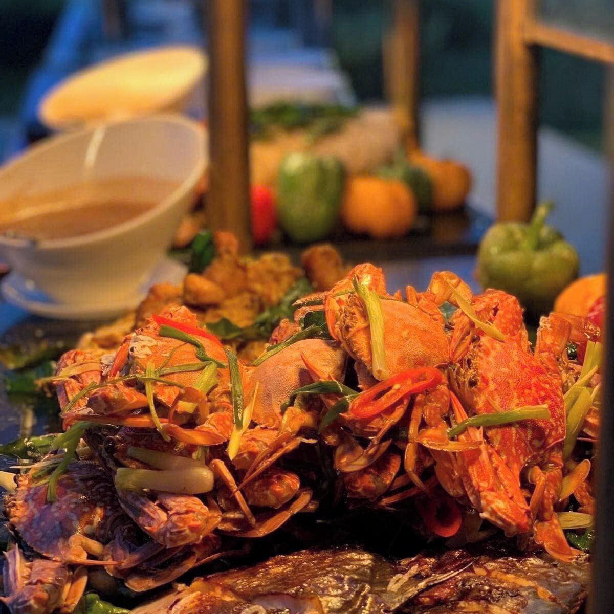 Un tavolo con piatti di pesce e crostacei cotti, guarnito con erbe aromatiche verdi.