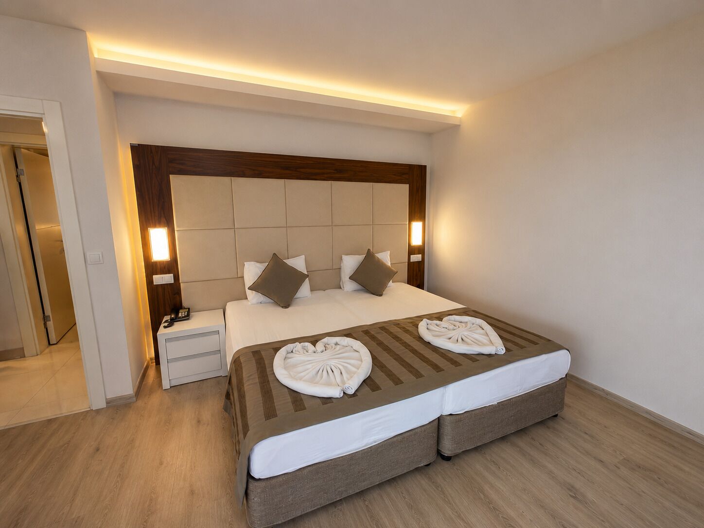 Una habitación de hotel con una cama grande, mesitas de noche y un cabecero de madera.