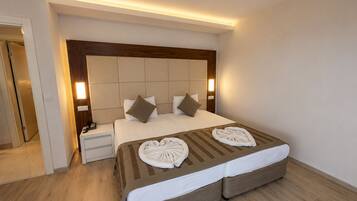 Una habitación de hotel con una cama grande, mesitas de noche y un cabecero de madera.