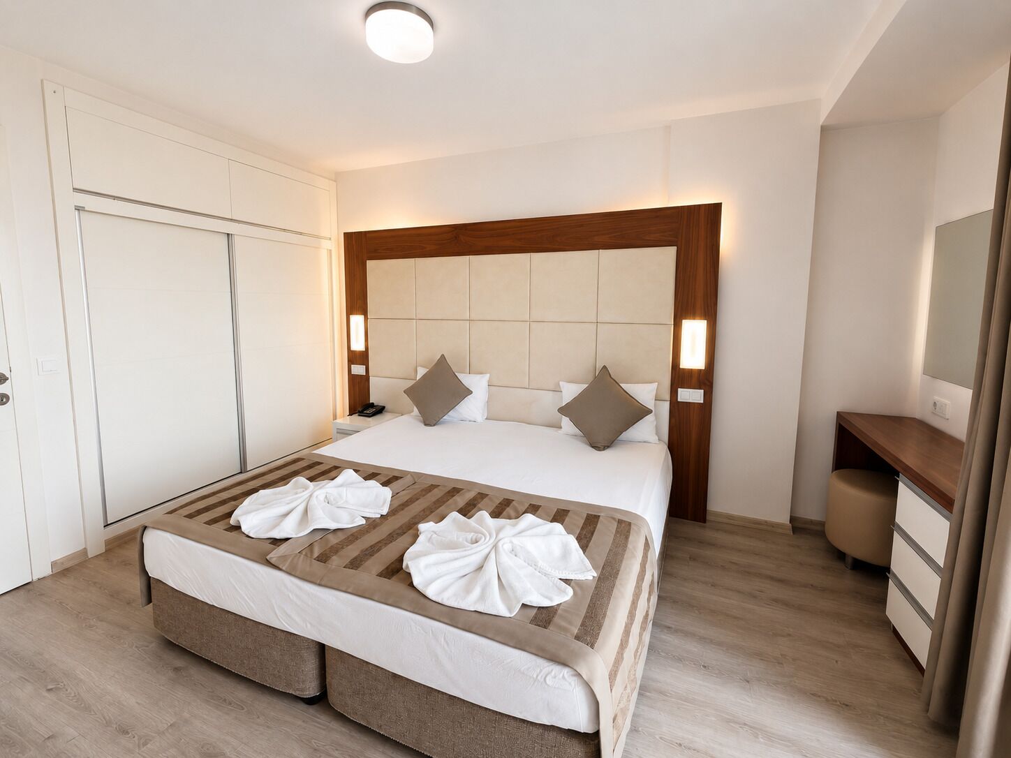 Ein Hotelzimmer mit Bett, Nachttischen, einem Kleiderschrank und einem Schreibtisch.
