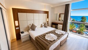 Ein Hotelzimmer mit einem großen Bett, einem Nachttisch, einem Spiegel und Blick auf den Ozean.