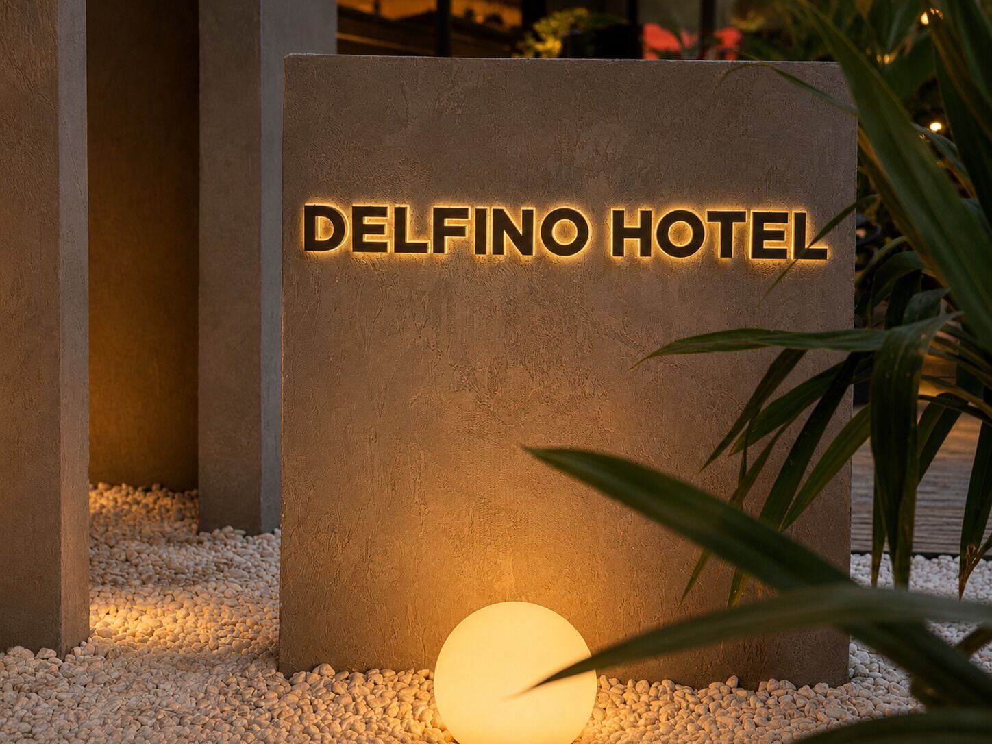 A sign for Delfino Hotel with a textured surface and illuminated letters.