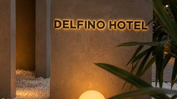 Une enseigne pour l’hôtel Delfino, avec une surface texturée et des lettres illuminées.