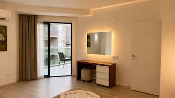 Een moderne hotelkamer met een bed, nachtkastje, spiegel, een schuifdeur naar een balkon en uitzicht op de omgeving.