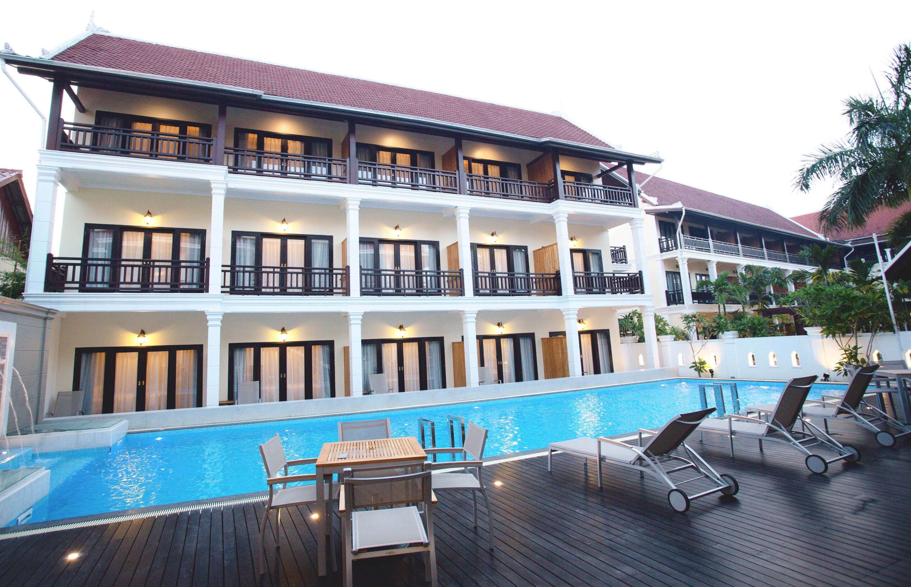 Ein mehrstöckiges Hotel mit Schwimmbad, Außenbereich zum Sitzen und einem Balkon mit Geländer.