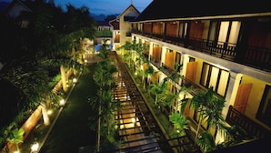 A hotel with a long corridor lined with palm trees and a wooden walkway.