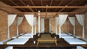 A spa area with wooden benches, a central table, and white curtains.